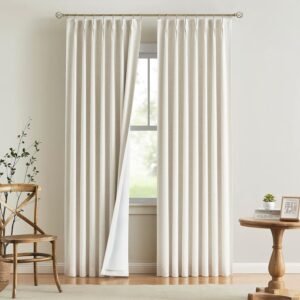 Cream blackout insulated curtain with white liner on gold rod in neutral room with wood furniture and hardwood floors