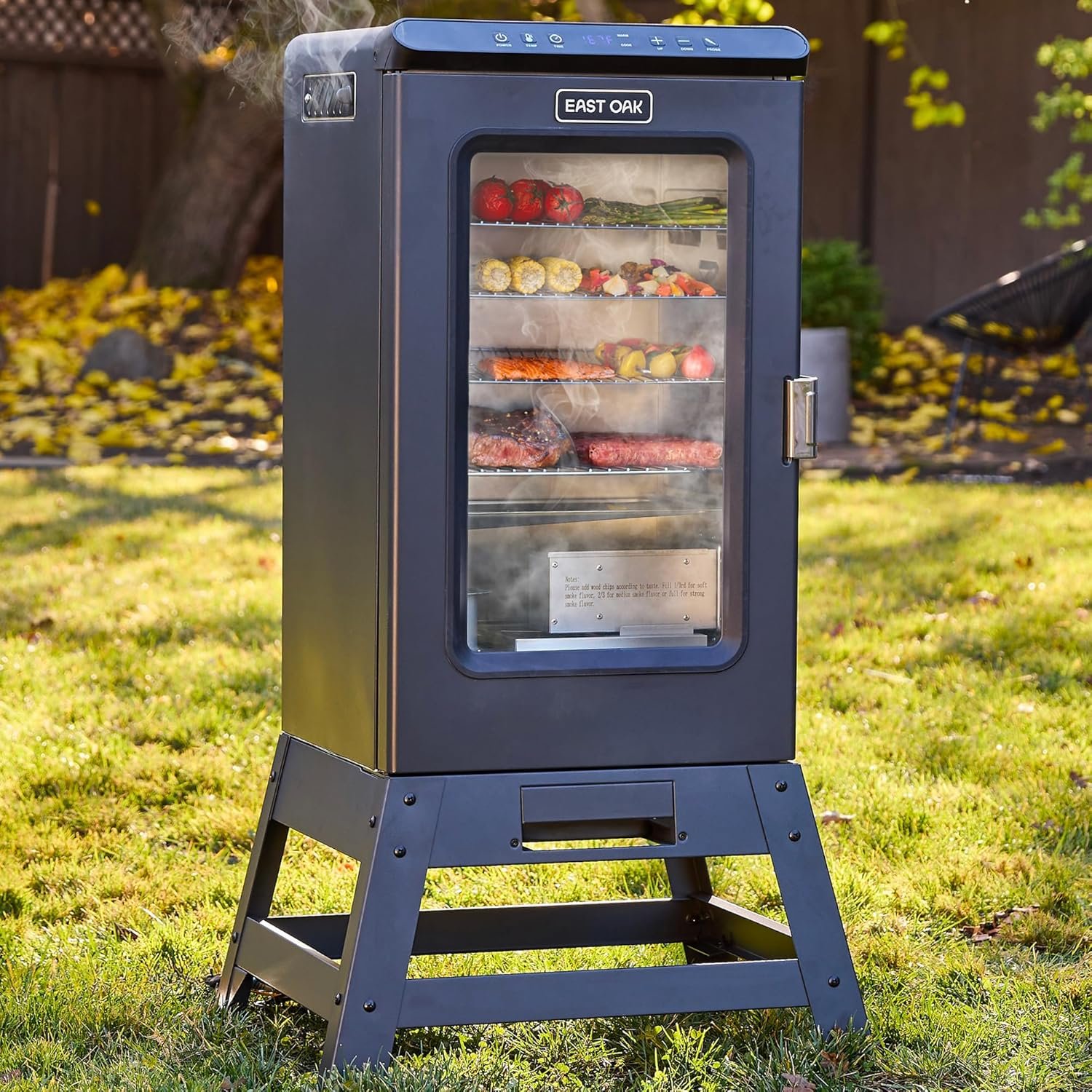 Navy blue EAST OAK electric smoker with glass window showing smoking food on racks, digital controls, and smoke