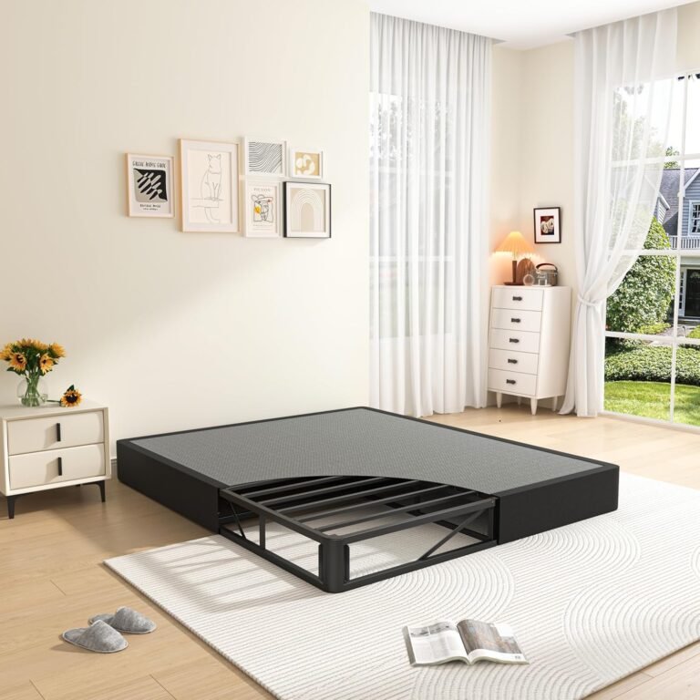 Black MAF metal mattress foundation in folding box spring design with grey quilted top, shown partially opened in a bright modern bedroom with white decor