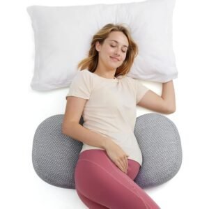 Gray knit U-shaped pregnancy pillow supporting woman lying on white bedding with belly and back support