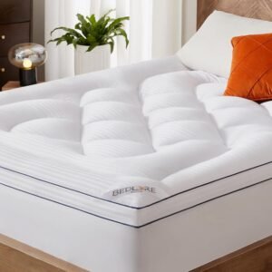 White quilted mattress topper with pillow-top cushioned squares on modern bed with orange accent pillow