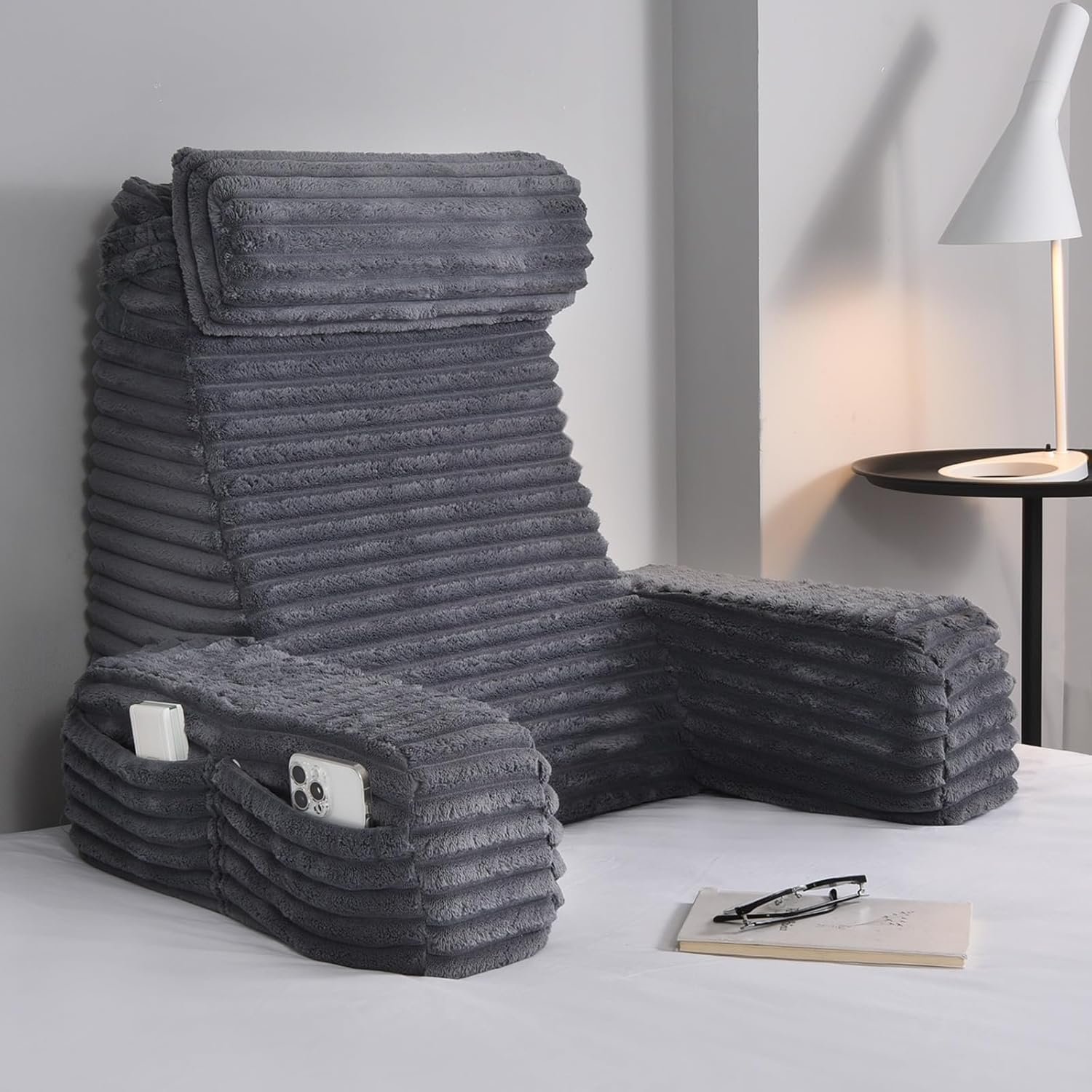 Charcoal grey ENITYA reading pillow with high backrest, padded armrests, and side pockets in modern grey room
