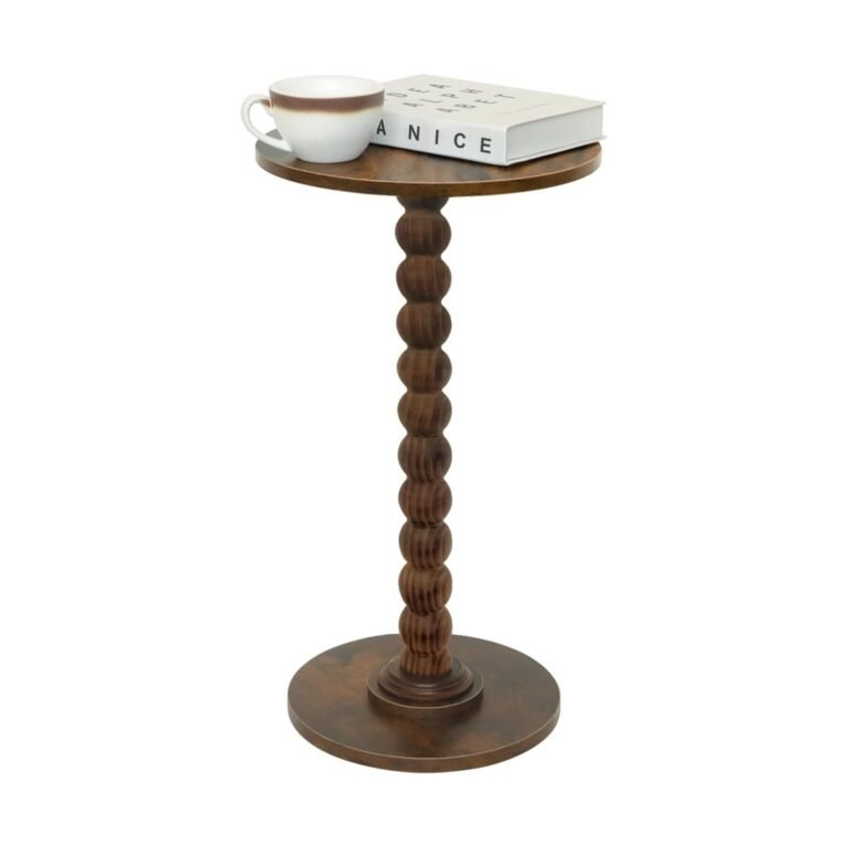Brown wooden pedestal round side table with carved spindle base displaying white coffee cup and books