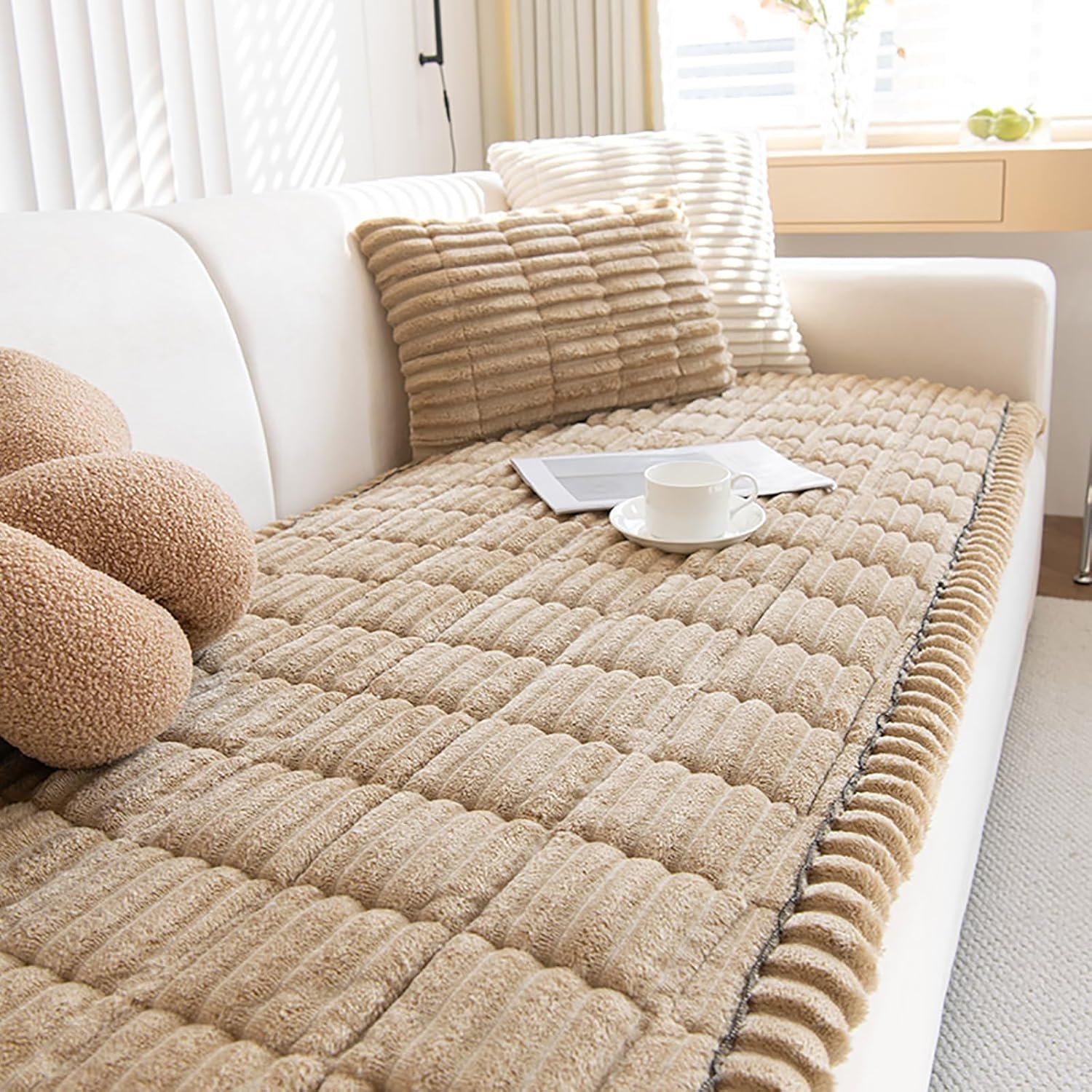 Beige quilted plush fleece washable pet couch cover with channel quilting, matching pillows, tablet, and coffee cup on white couch