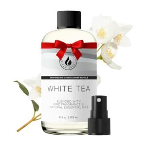 Frosted glass bottle of Aroma Country essential oil (white tea) with red ribbon bow, spray pump, and white jasmine flowers